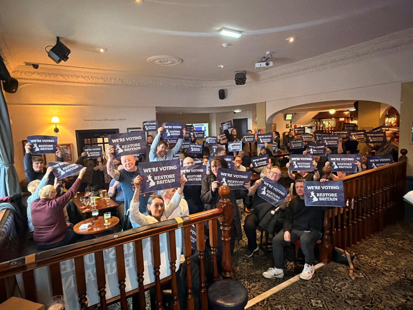 Members of Restore Britain Blackpool and Fleetwood at a branch meeting, holding We are voting Restore Britain placards